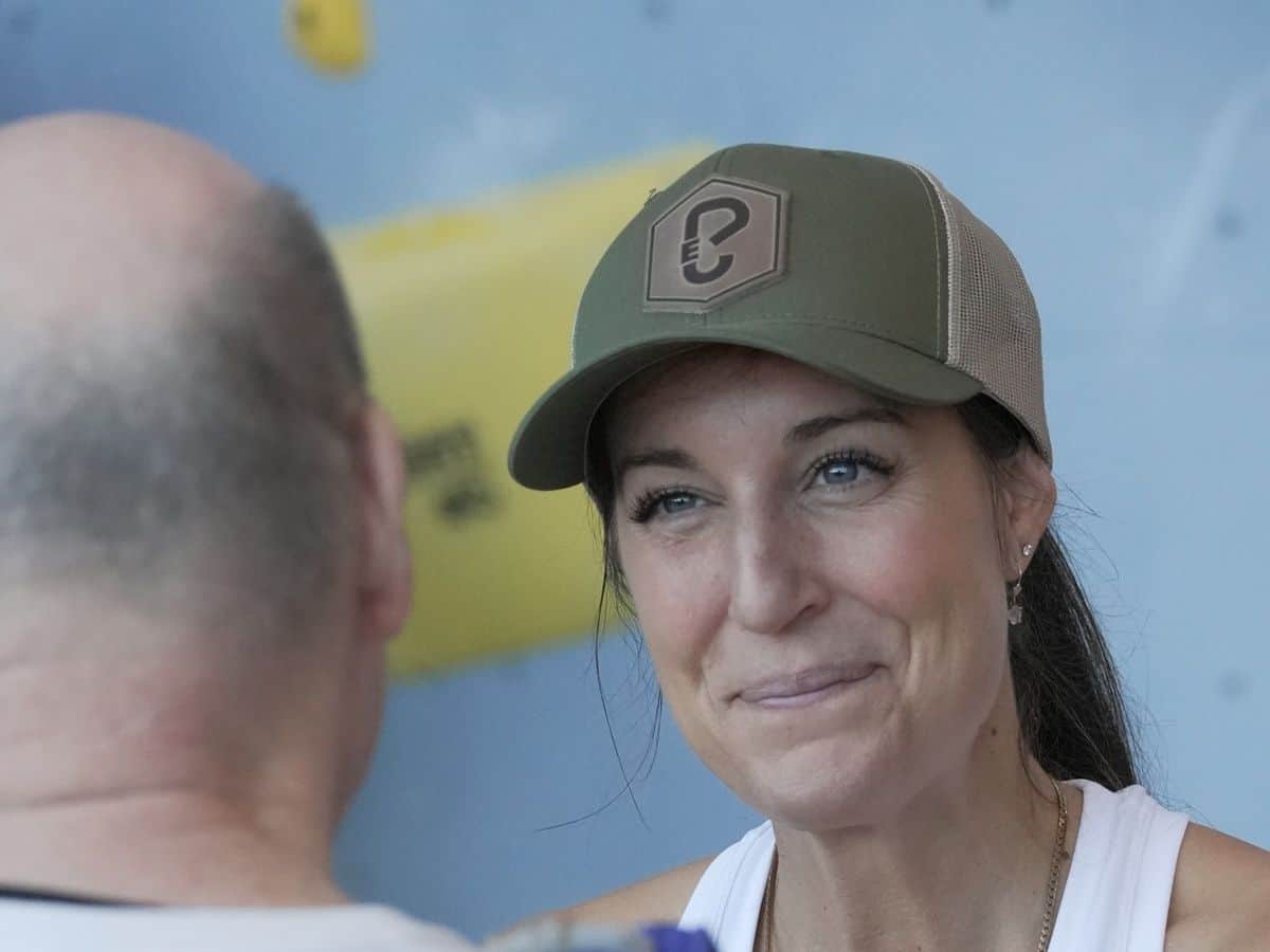 Molly Cupka in der Kletterhalle Molly Cupka mit Basecap lächelt einem Teilnehmer in der Kletterhalle zu