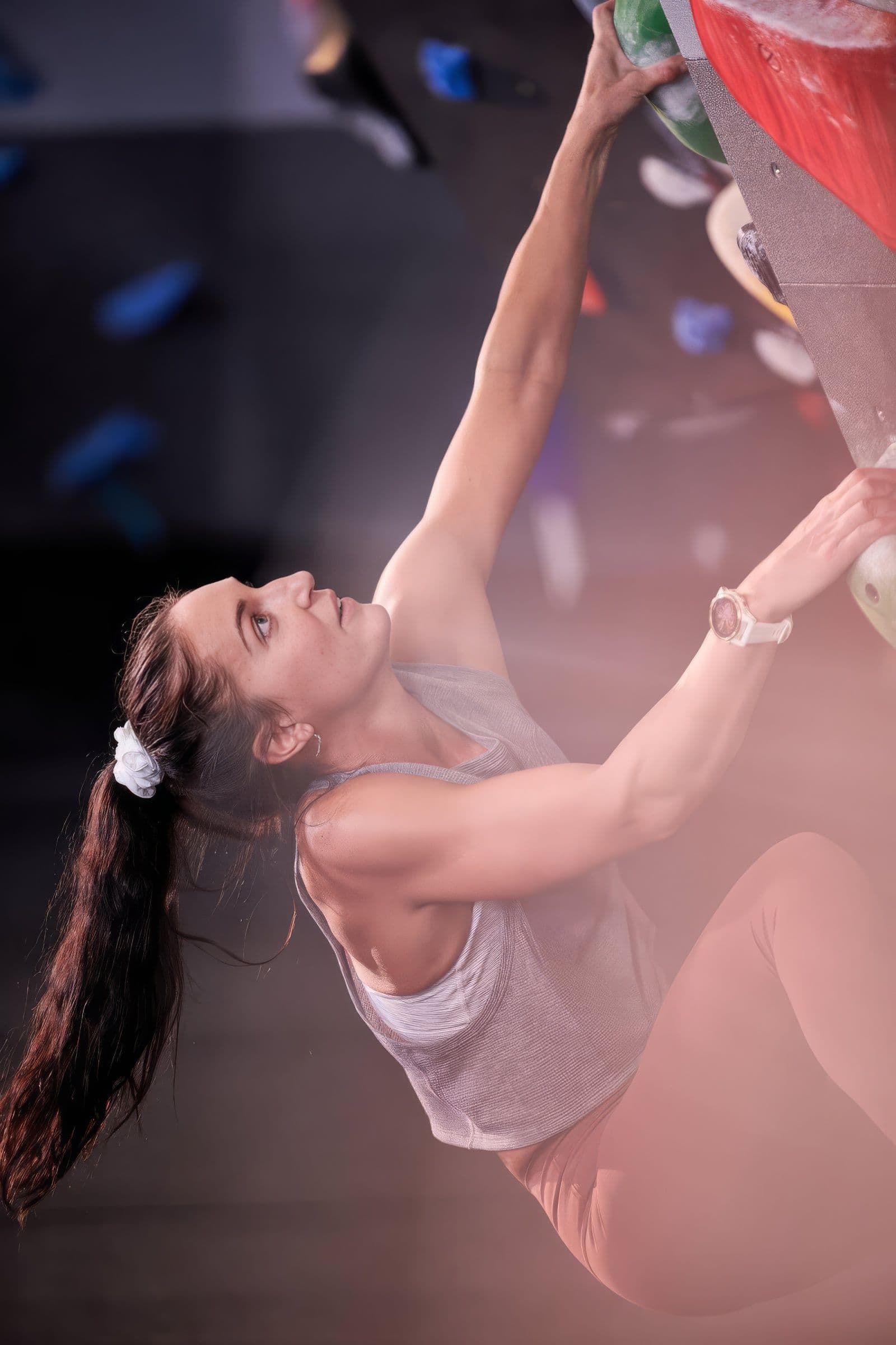 Molly Cupka climbing a wall, reaching for a hold above her head