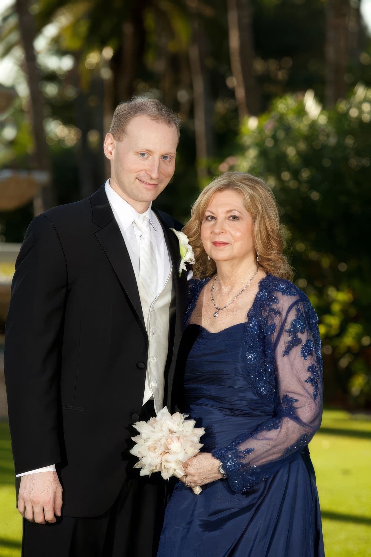 George Ackerman in a suit beside his mother Sharon in a blue dress at a family celebration